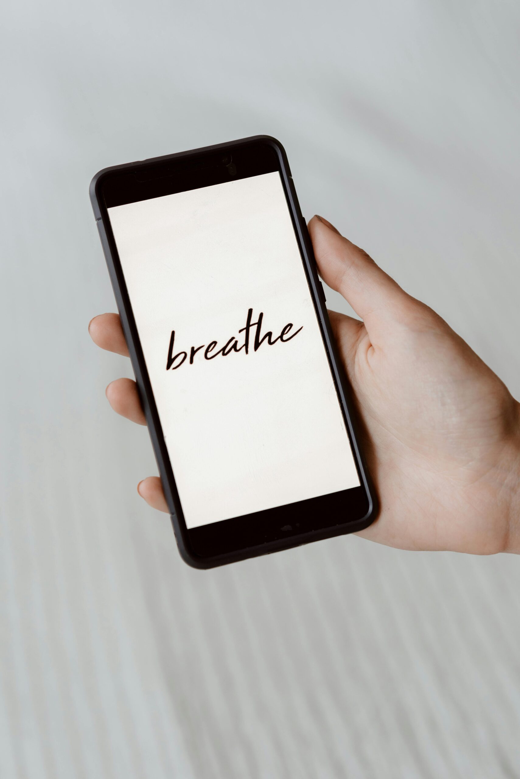 Hand hält Smartphone mit dem Wort "breathe" auf dem Bildschirm.
