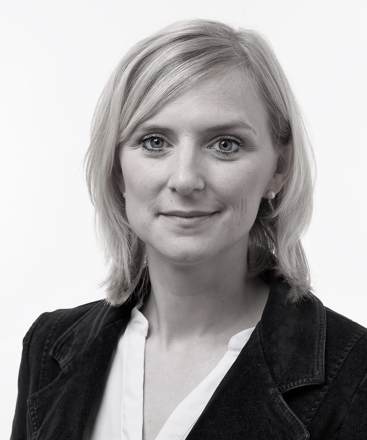 Eine Frau mit schulterlangem Haar in Schwarz-Weiß, trägt Blazer und Bluse.